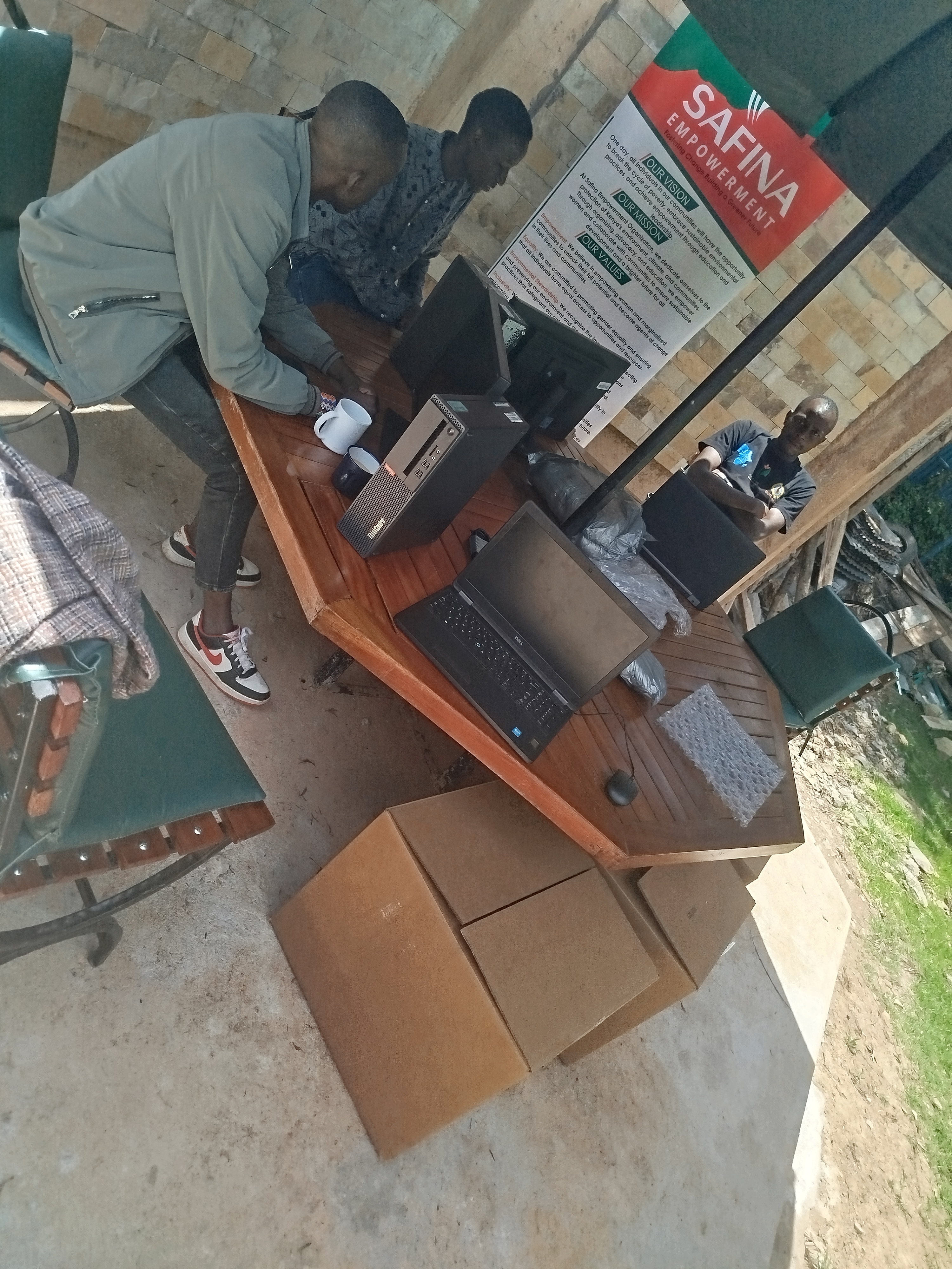 Safina team members setting up desktop and laptop computers beside a Safina Development banner